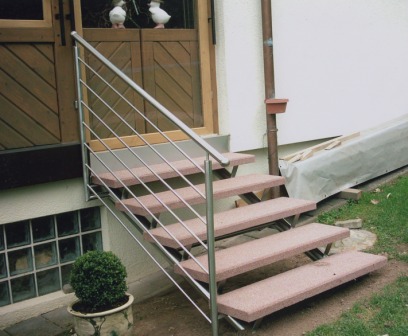 Außentreppe in Edelstahl als Metalltreppe bzw. Rundholwangentreppe mit Edelstahlgeländer und Steinstufen