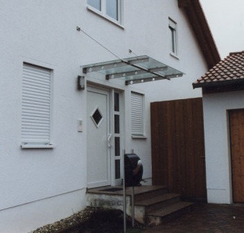 Vordach in Edelstahl mit einem Seil nach hinten abgehangen, Vordach in Glas
